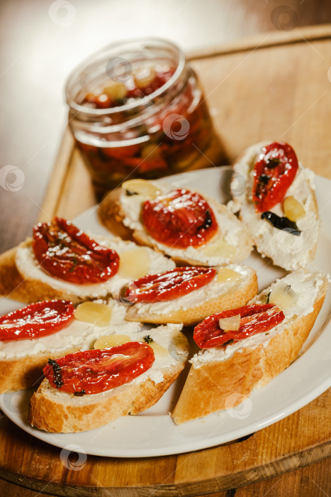 Скачать бутерброды с вялеными помидорами и сыром на тарелке на столе фотосток Ozero