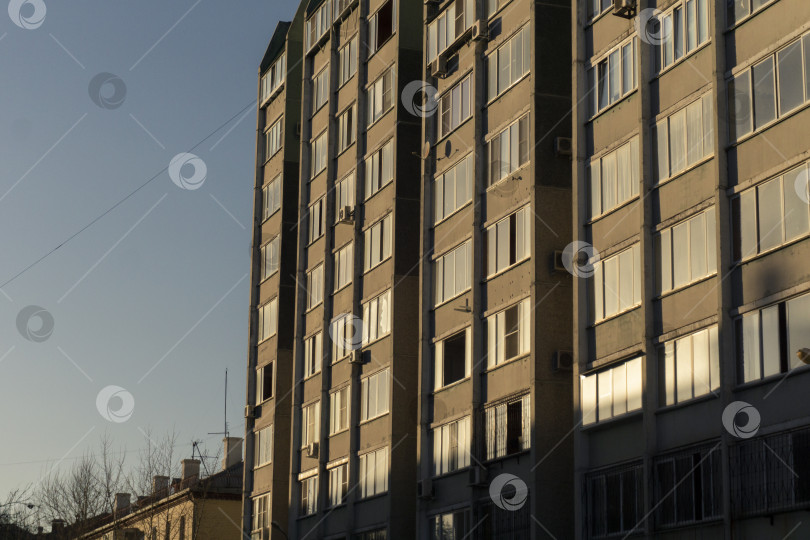 Скачать Свет от заката падает на панельное высотное здание и его окна. фотосток Ozero