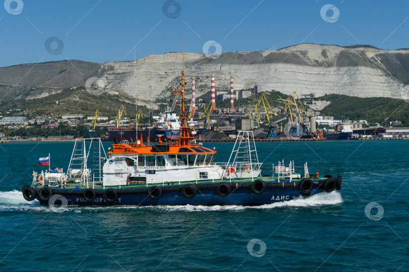 Скачать Морской лоцман "Адис" плывет по голубым водам Черного моря. Белое рабочее судно "Адис" в Новороссийском морском торговом порту на фоне Кавказских гор.  Новороссийск, Россия - 15 сентября 2021 г. фотосток Ozero