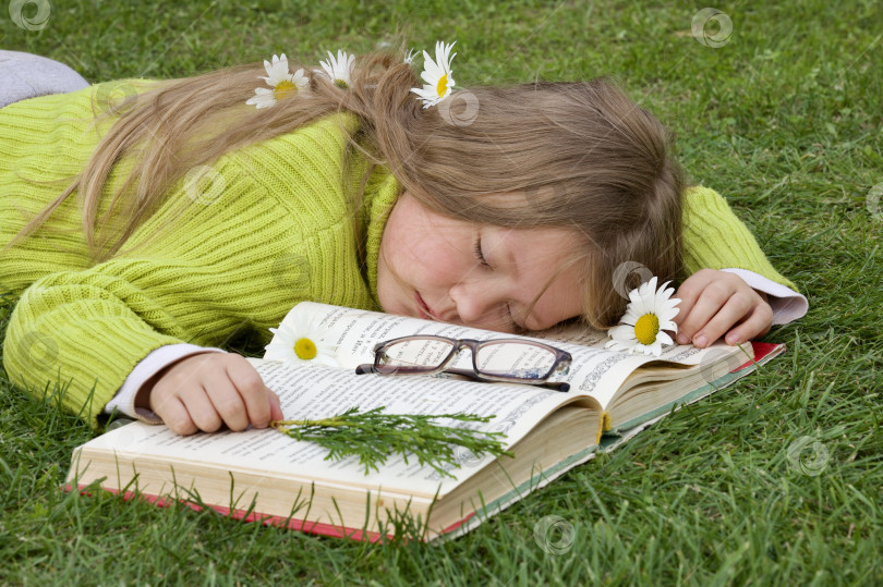 Скачать Девочка, ребёнок уснула за чтением книги на зелёной траве, газоне. фотосток Ozero