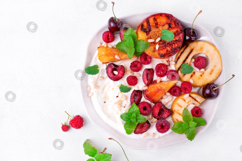 Скачать Запеченные персик и яблоко в творожном креме с малиной, вишней, мятой и кедровыми орешками. фотосток Ozero
