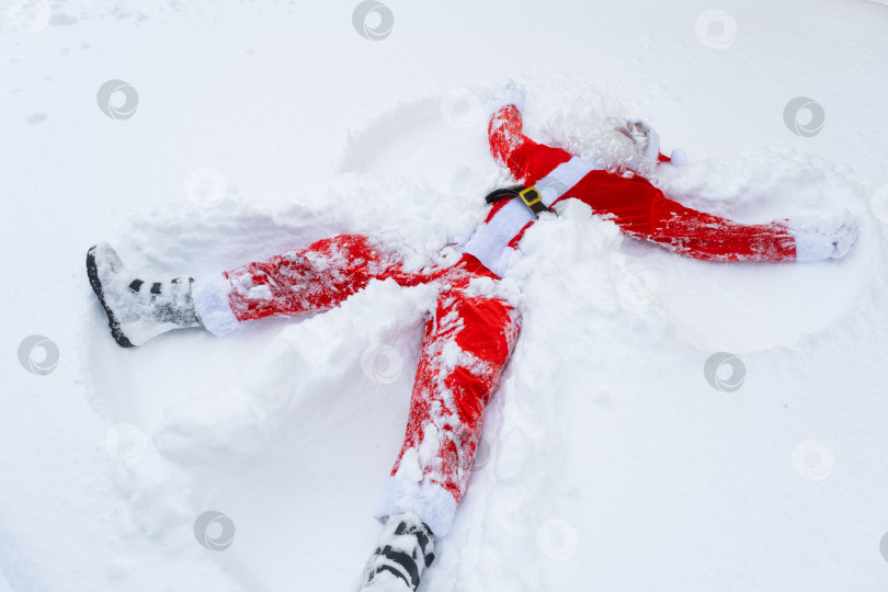 Скачать Санта Клаус лепит снежных ангелов из снега. Юмор, зимние забавы, Санта устал и пьян фотосток Ozero