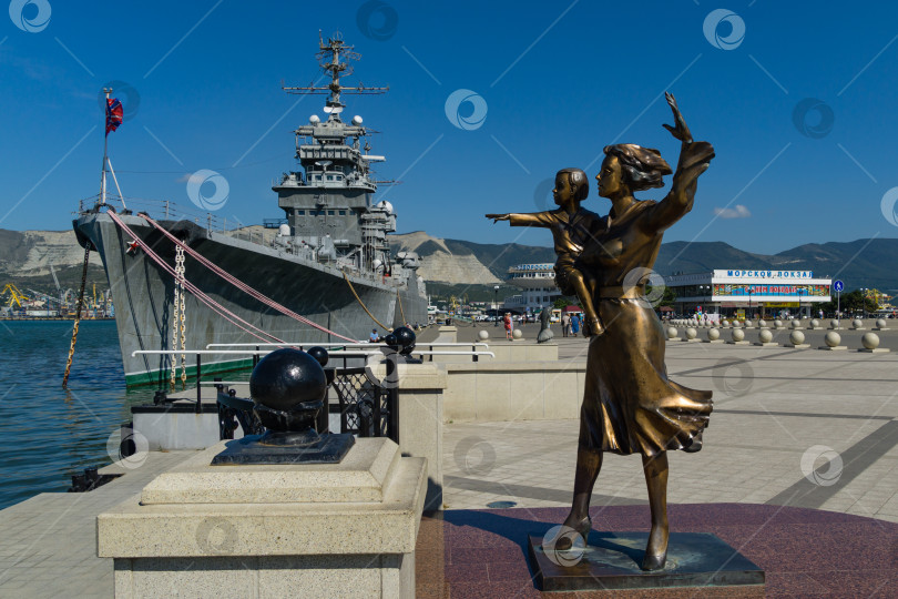 Скачать Памятник жене моряка на набережной в Новороссийске. Скульптура красивой женщины с ребенком на фоне крейсера "Михаил Кутузов". Новороссийск, Россия - 15 сентября 2021 года фотосток Ozero