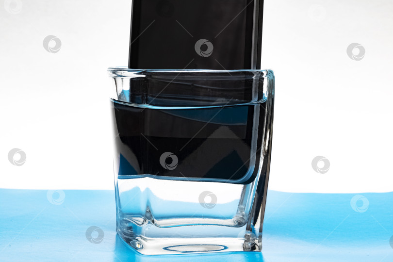 Скачать Мобильный телефон в стакане с водой фотосток Ozero