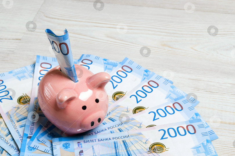 Скачать Розовая копилка с российскими денежными купюрами номиналом в две тысячи. фотосток Ozero