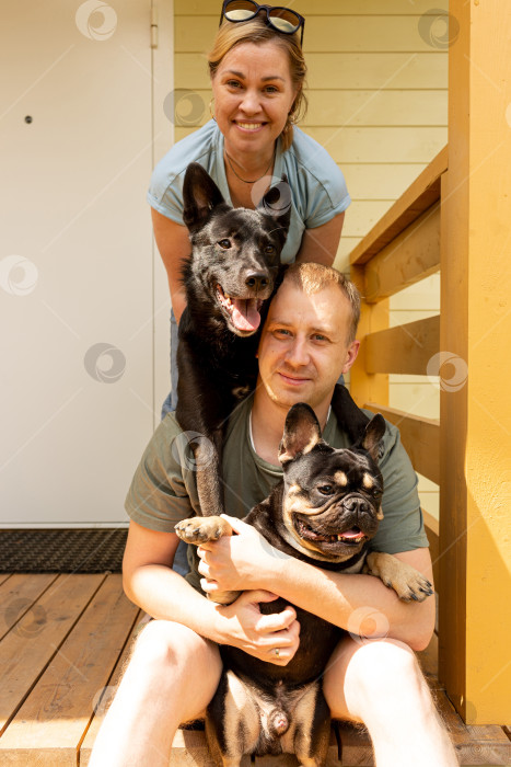 Скачать Мужчина и женщина со своими собаками на крыльце дома фотосток Ozero