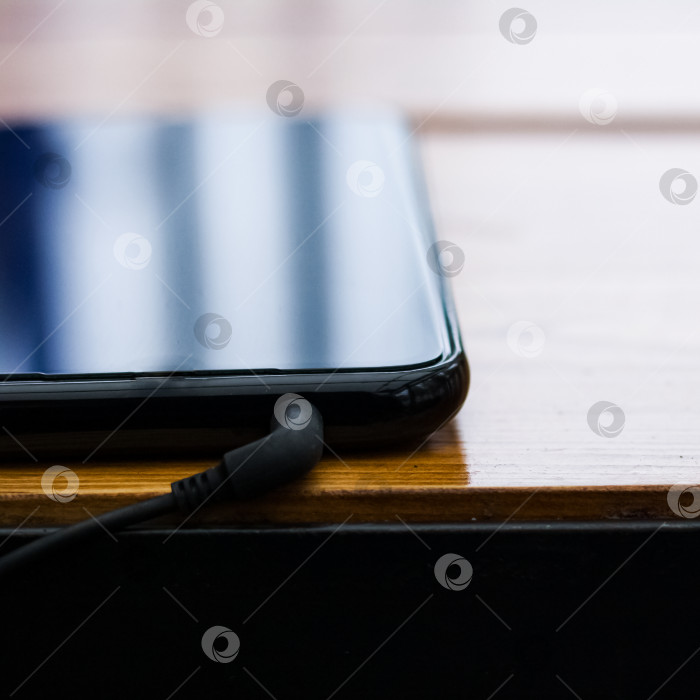Скачать Черный смартфон с наушниками на деревянном столе фотосток Ozero
