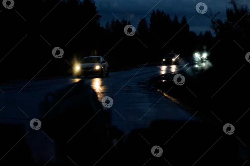 Скачать Переднее стекло автомобиля с каплями дождя и дорога с автомобилями ночью фотосток Ozero