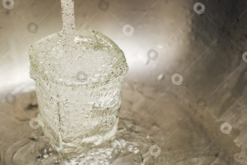 Скачать Струйка воды стекает в стеклянную чашку фотосток Ozero