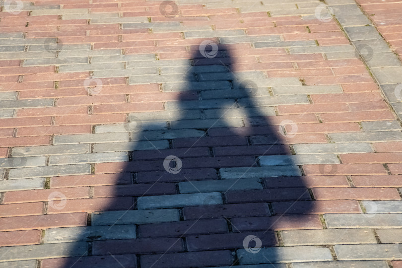 Скачать Тень человека на выложенном плиткой тротуаре фотосток Ozero
