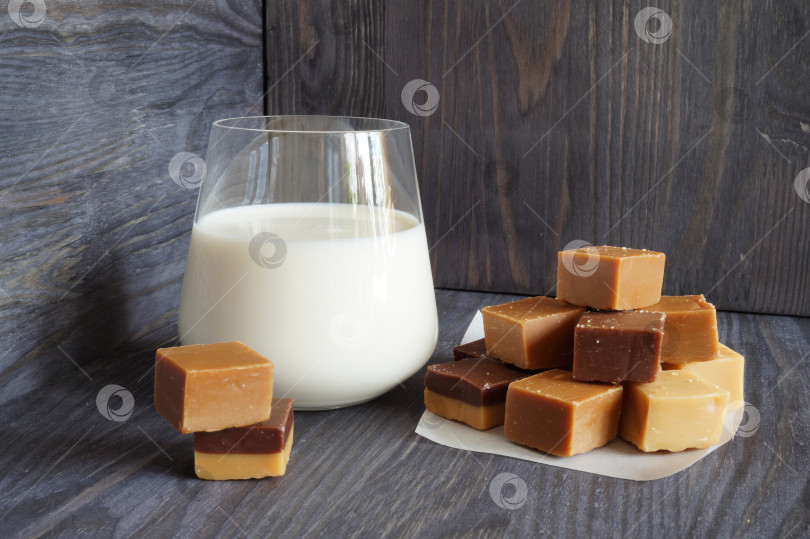 Скачать Стакан молока и горка ирисок на деревянном фоне фотосток Ozero