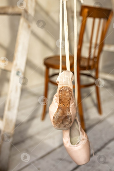 Скачать Балетные туфли висят на перекладине в танцевальном зале. Концепция танца, балетная школа, обувь для балерин. Новые пуанты с подвешенными к ним атласными лентами. фотосток Ozero