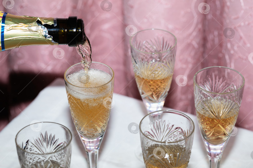 Скачать Процесс розлива шампанского в хрустальные бокалы на фоне занавески - концепция в стиле девяностых фотосток Ozero