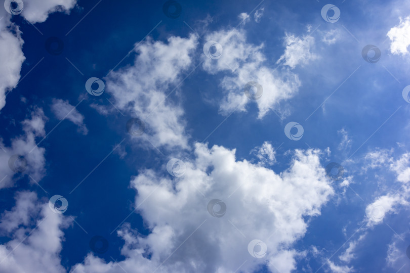 Скачать Белые облака причудливой формы на фоне голубого неба в ясный солнечный день. фотосток Ozero