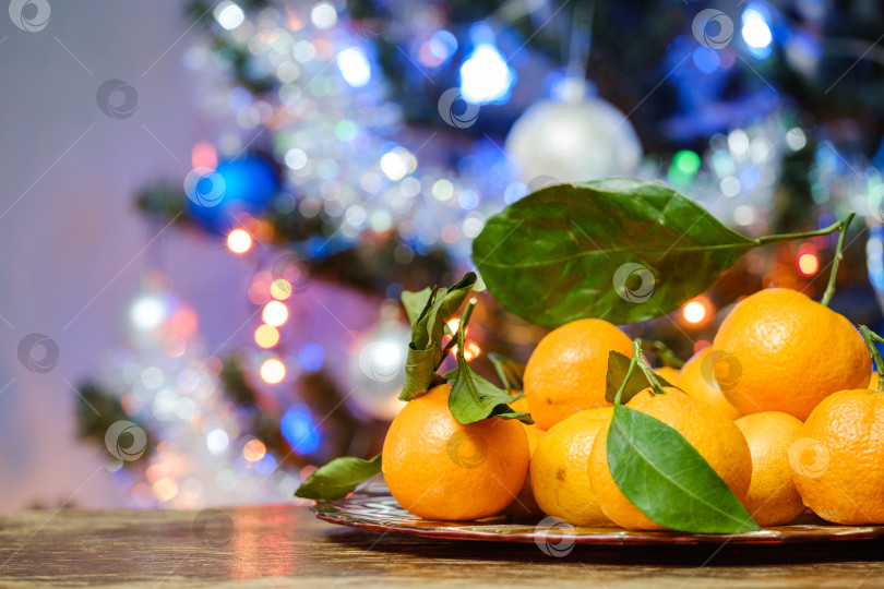 Скачать мандарины на столе на фоне рождественской елки фотосток Ozero
