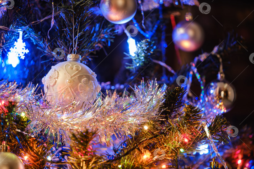 Скачать Новогодний шар на елке с блестящей мишурой и гирляндой фотосток Ozero