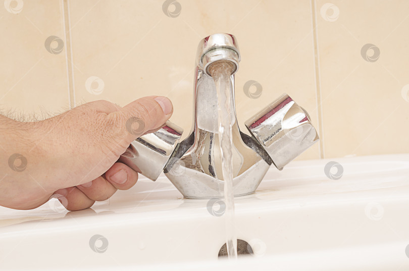 Скачать мужчина закрывает кран из нержавеющей стали с водой в ванной.Экономия воды в доме фотосток Ozero