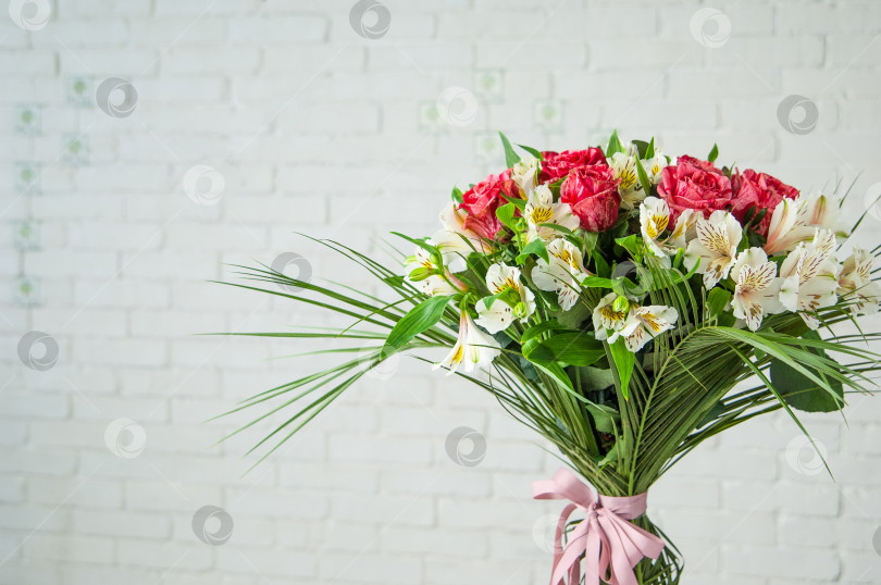 Скачать Красивый букет из роз и белых альстромерий на фоне белой стены фотосток Ozero