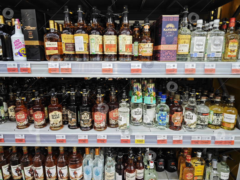 Скачать Бутылки из-под алкогольных напитков с текилой, джином и ромом на полке в супермаркете фотосток Ozero