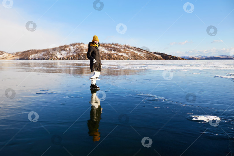 Скачать Радостная девушка стоит на льду замерзшего озера Байкал. Он держит в руках коньки. фотосток Ozero