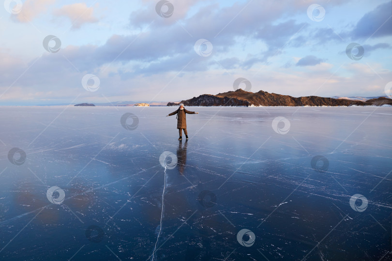 Скачать Счастливая молодая женщина прогуливается по прозрачному льду озера Байкал. Путешествия зимой , активный отдых. фотосток Ozero