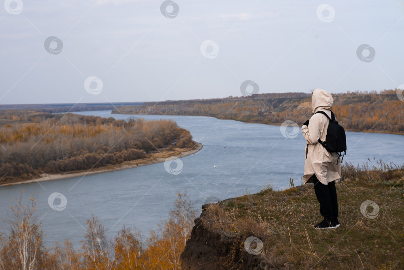 Скачать Молодая девушка стоит на высоком берегу и смотрит на прекрасную природу фотосток Ozero