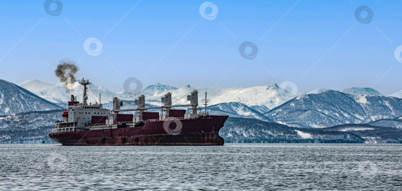 Скачать контейнеровоз в бухте напротив заснеженных гор на полуострове Камчатка фотосток Ozero