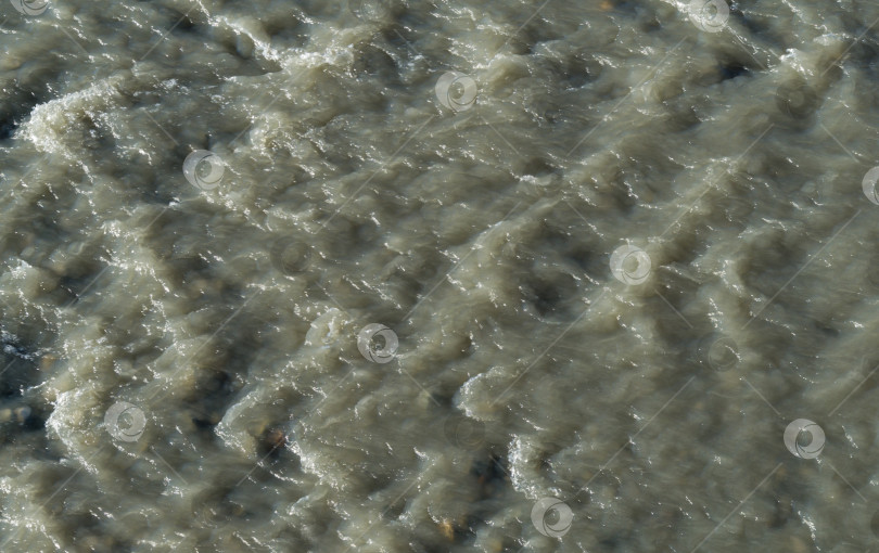 Скачать Крупный план мутной, бурлящей горной реки Мзымта в Адлере. среди скал на мелководье. Интересный серый фон с быстрыми пятнами для любого дизайна. фотосток Ozero