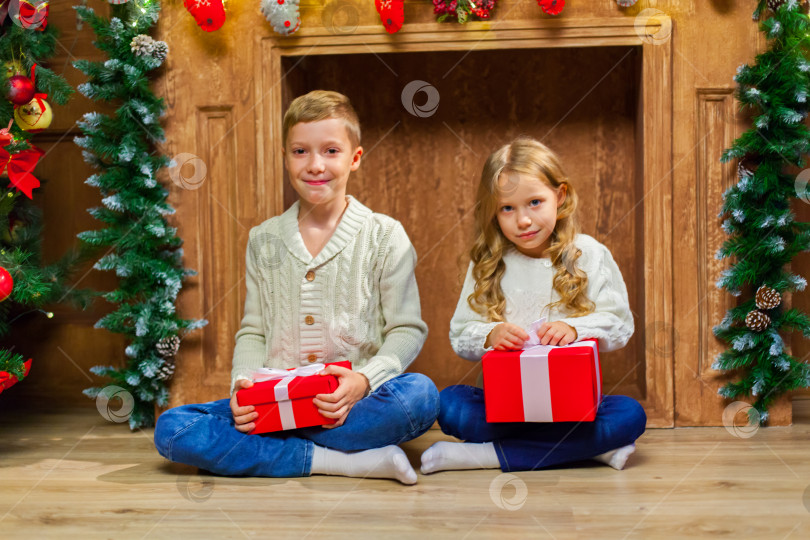 Скачать Портрет счастливых детей с подарками вокруг рождественской елки у камина фотосток Ozero