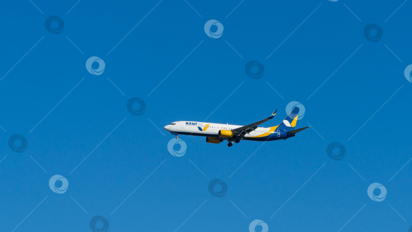 Скачать Boeing 737-900ER заходит на посадку на взлетно-посадочной полосе аэропорта Адлер на фоне голубого весеннего неба. Boeing 737-900ER VQ-BYO Azur Air. Сочи, Россия - 18 мая 2021 г. фотосток Ozero