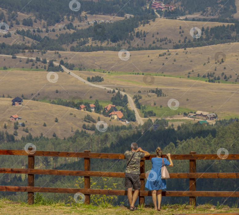 Скачать туристы, семейная пара сесей у забора, смотрят на деревенский пейзаж фотосток Ozero