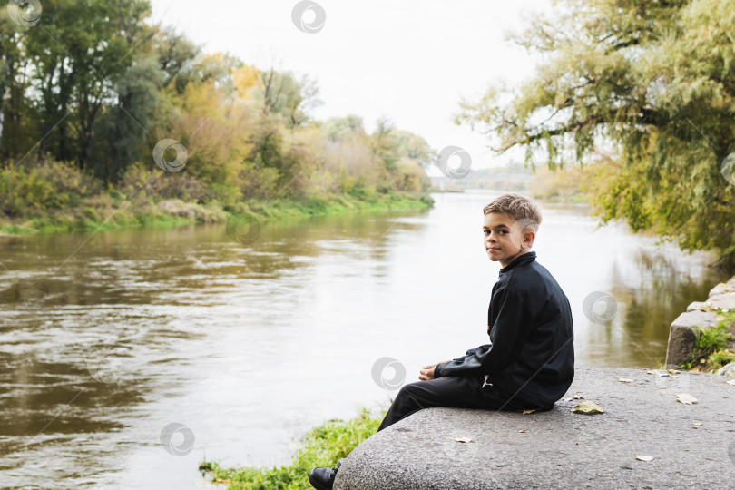 Скачать Маленький мальчик сидит на берегу реки фотосток Ozero