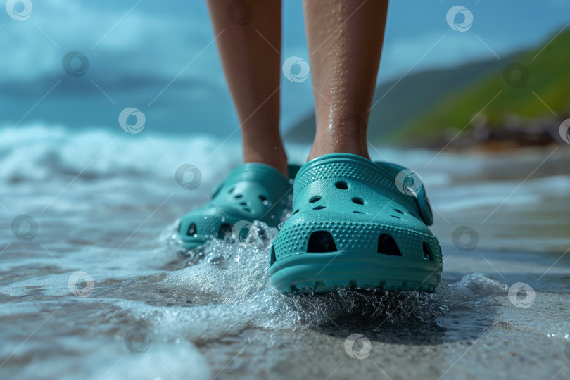 Скачать обутые в кроксы ноги человека на пляже, идущего вдоль полосы прибоя фотосток Ozero