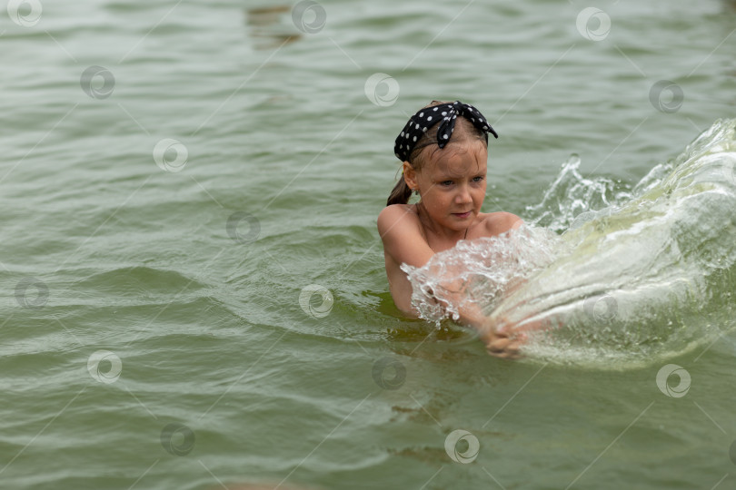 Скачать Девочка плавает в пруду, разбрызгивая воду. Выходные на водохранилище. Летние каникулы фотосток Ozero