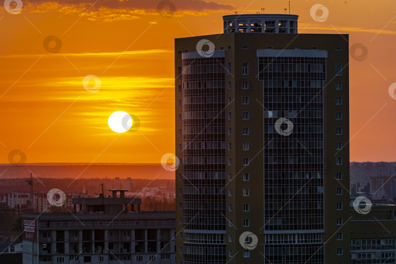 Скачать Закат среди многоэтажных городских зданий. Белое солнце и оранжевое небо. фотосток Ozero