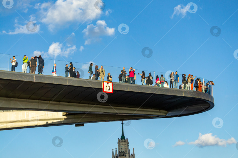 Скачать Люди стоят на плавучем мосту и фотографируются на фоне голубого неба и белых облаков. Крупный план. фотосток Ozero