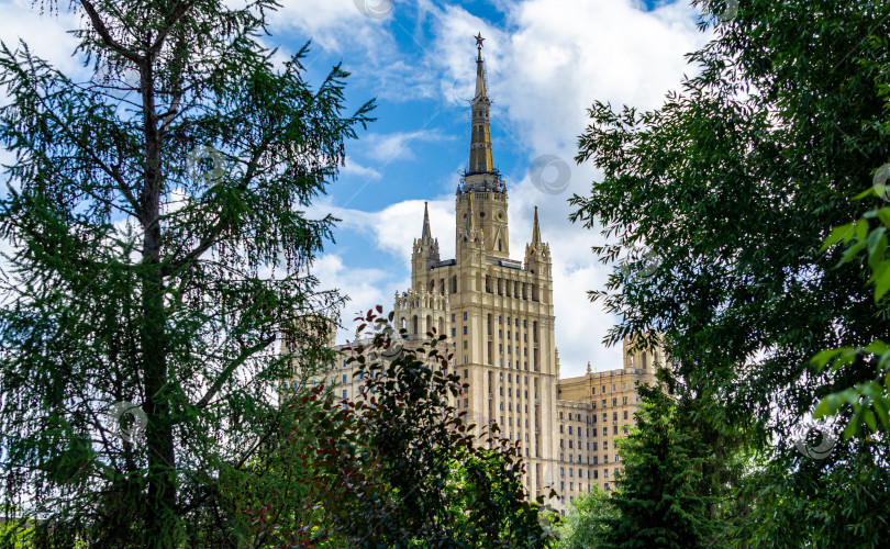 Скачать Вид с территории Московского зоопарка на жилой дом среди листвы деревьев. Высотное здание на Кудринской площади. фотосток Ozero