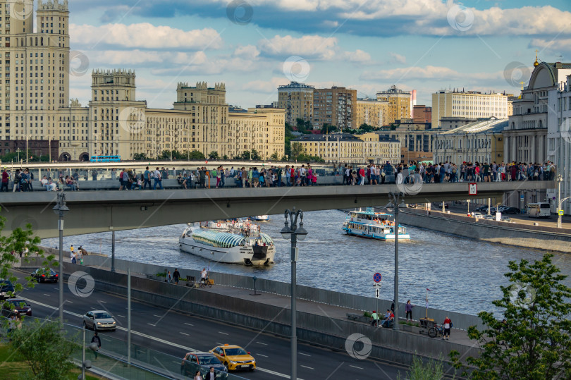 Скачать Парк Зарядье. Наплавной мост с людьми. Прогулочные катера плывут по Москве-реке. Автомобили на рельсах под наплавным мостом. Сталинская высотка на Котельнической набережной. фотосток Ozero