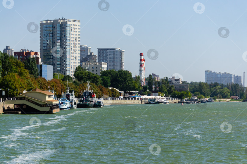 Скачать Высотные здания на набережной реки Дон. Вдоль набережной, причалы с буксирами, скоростные яхты и прогулочные катера на фоне голубого неба. фотосток Ozero