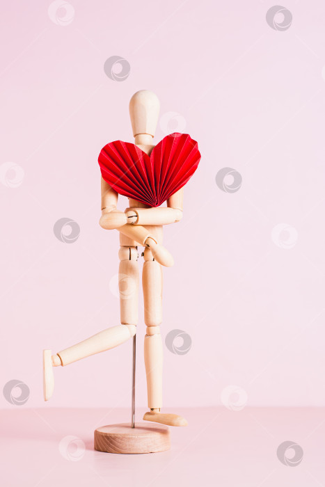 Скачать Деревянный манекен с красным сердцем оригами на розовом фоне вертикальный вид фотосток Ozero