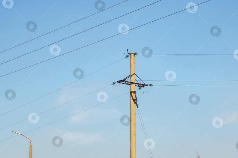 Скачать Столб с электрическими проводами на фоне голубого неба фотосток Ozero