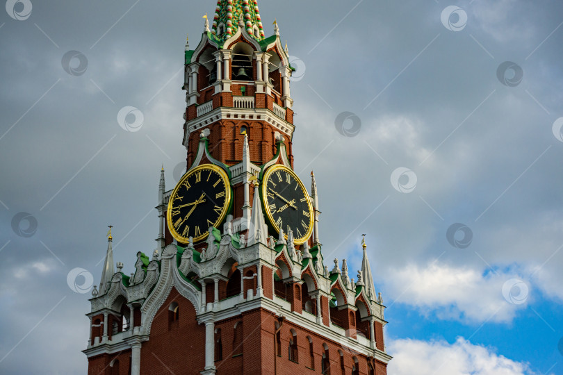 Скачать Часы на Спасской башне Московского Кремля крупным планом в тени облаков, закрывающих голубое небо. Есть место для текста. фотосток Ozero