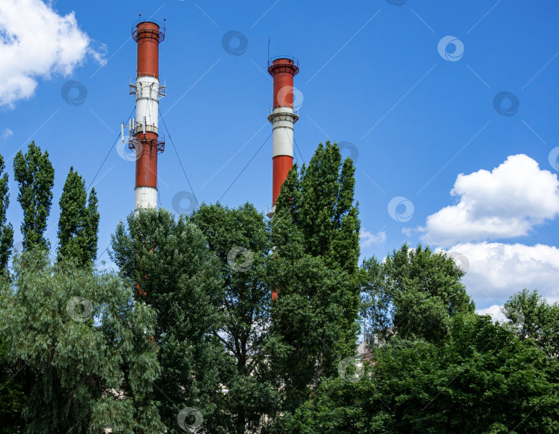 Скачать Крупным планом две трубы городской теплоэлектростанции на фоне голубого неба с белыми облаками. фотосток Ozero