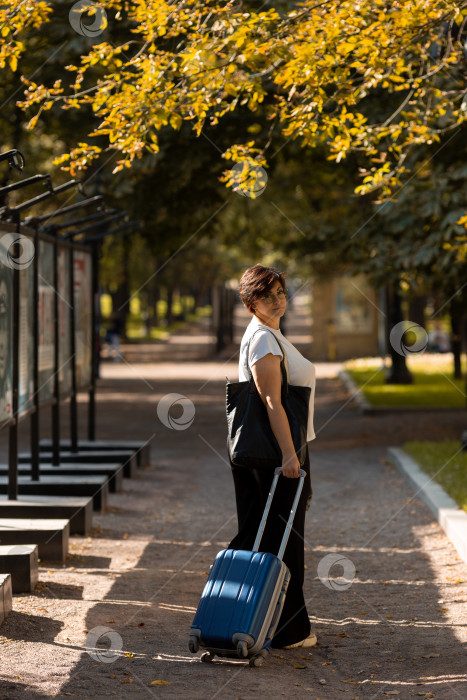 Скачать Женщина средних лет идет по бульвару с чемоданом фотосток Ozero