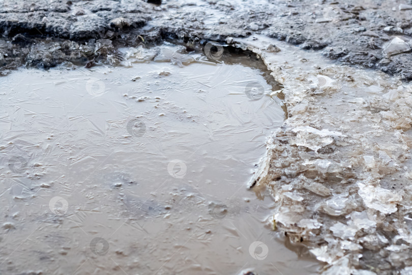 Скачать Замерзшая лужа на дороге крупным планом фотосток Ozero