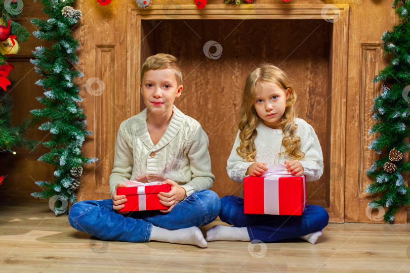 Скачать Портрет счастливых детей с подарками вокруг рождественской елки у камина фотосток Ozero