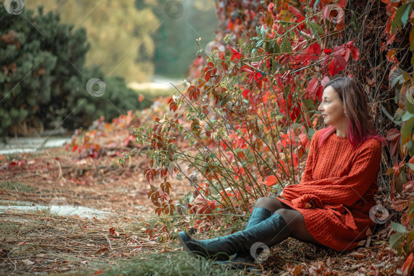 Скачать Женщина в ярком терракотовом платье на фоне красных и желтых осенних виноградных листьев. Осень фотосток Ozero