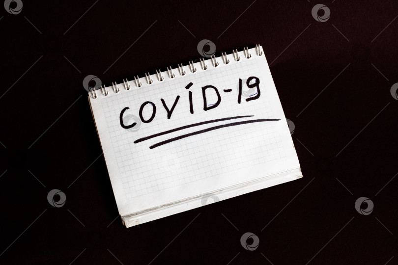 Скачать Слово covid-19 написано на листе блокнота на черном фоне фотосток Ozero