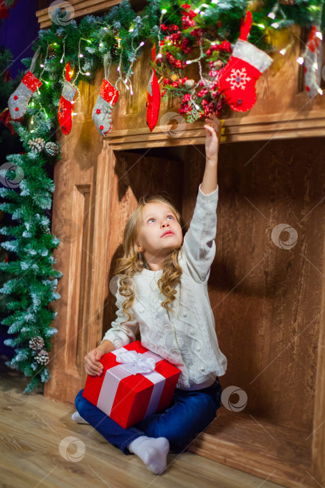 Скачать Счастливого Рождества счастливая девушка с волшебным подарком дома у рождественской елки и камина фотосток Ozero