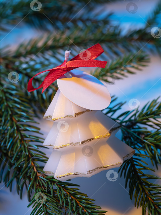 Скачать Белая ароматическая свеча в форме декоративной рождественской елки на еловой ветке крупным планом фотосток Ozero